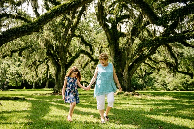Woman and girl walk hand in hand under live oaks at Jungle Gardens of Avery Island
