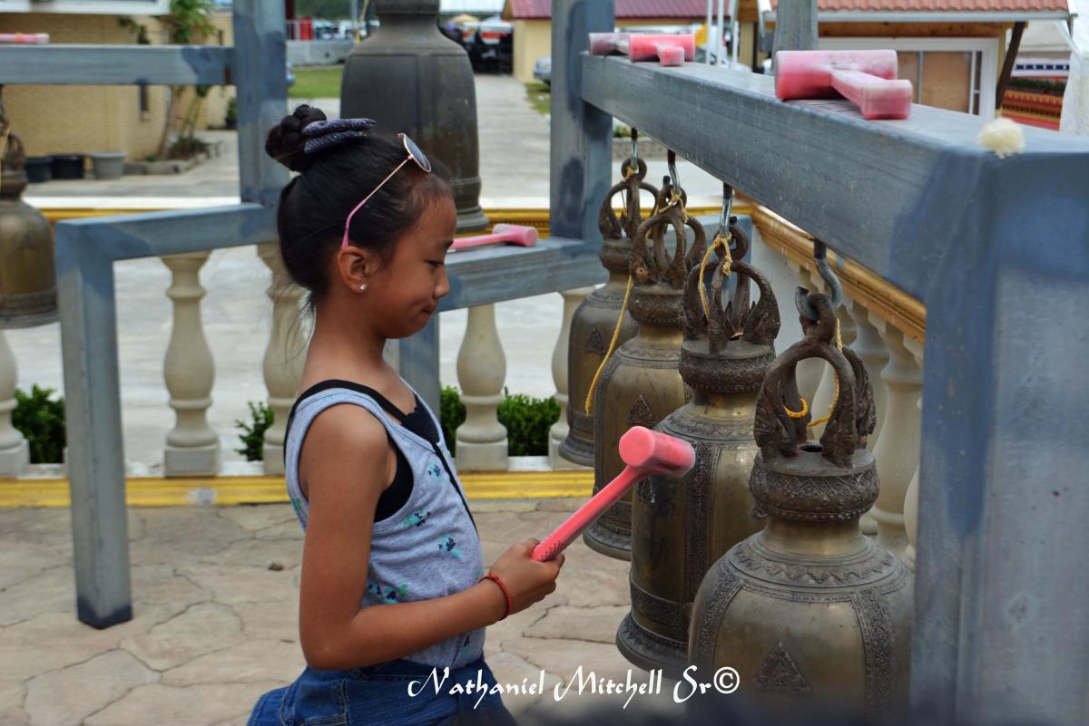 Child rings the bells at Lao Temple in Coteau