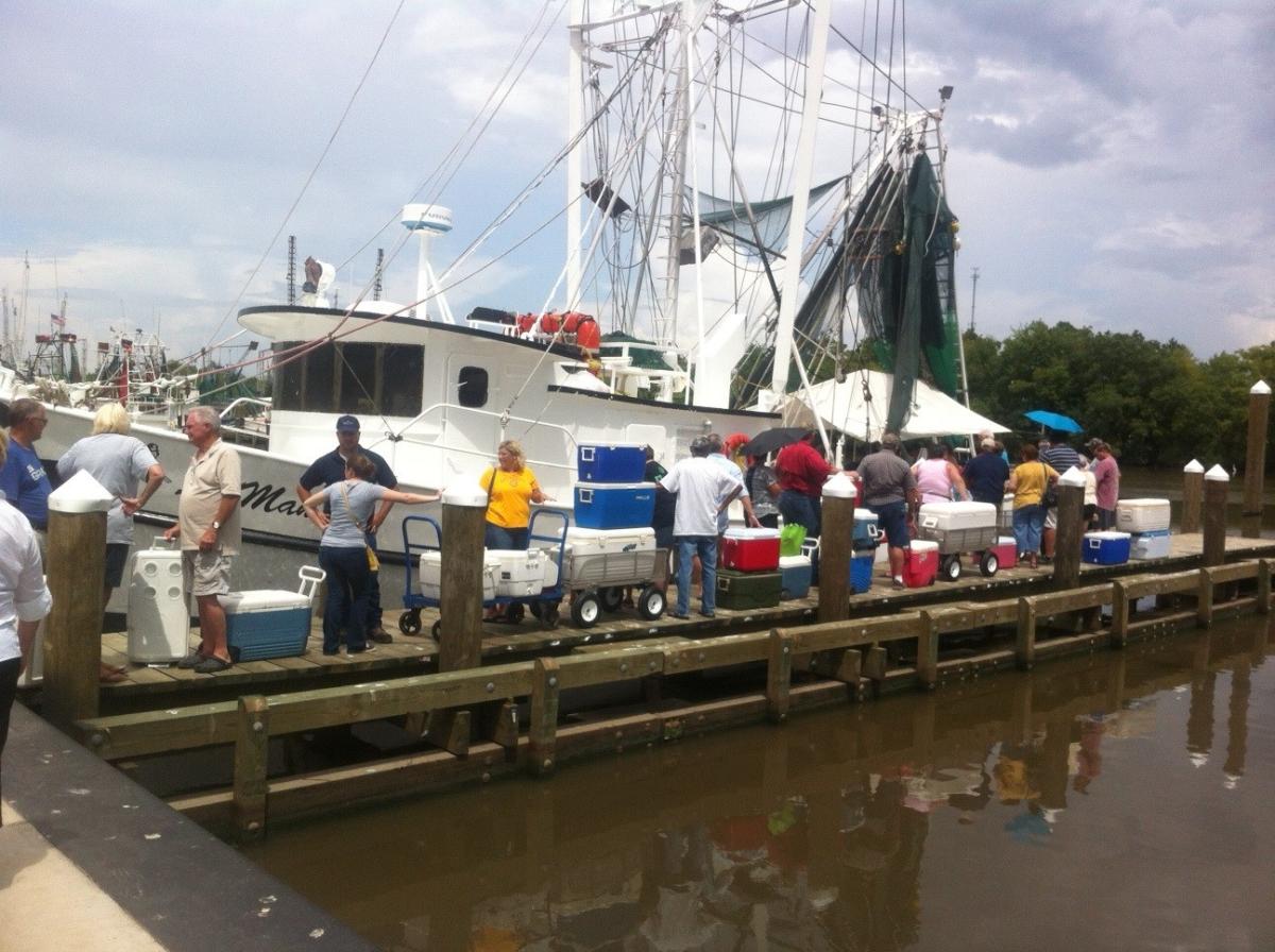 People standing in line in front of shrimp boat waiting to purchase seafood at market