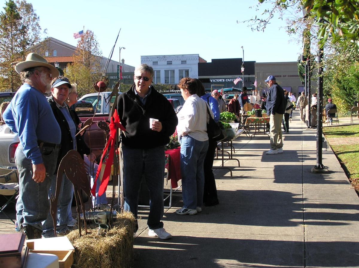 People shopping at the Teche Area Farmers Market with vendors at tables on the sidewalk