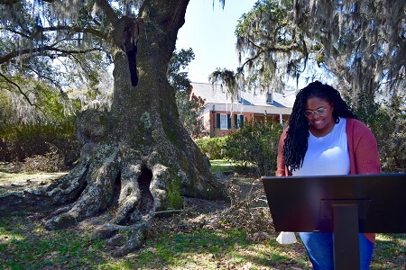 Young Black woman looks at interpretive panel in the gardens of Shadows on the Teche plantation home